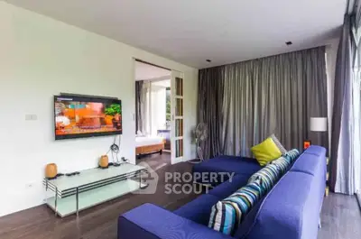 Modern living room with stylish blue sofa and wall-mounted TV in a bright apartment.