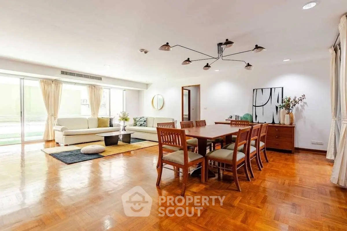 Spacious living and dining area with elegant wooden flooring and modern decor.