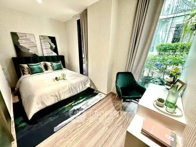 Luxurious bedroom with modern decor and large window overlooking lush greenery.