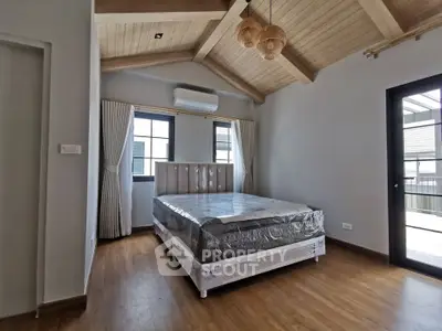 Spacious bedroom with vaulted ceiling and natural light, featuring modern design and wooden flooring.