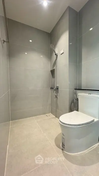 Modern minimalist bathroom with sleek gray tiles and contemporary fixtures.