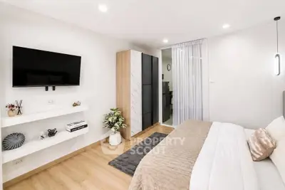 Modern bedroom with sleek design, wall-mounted TV, and cozy decor