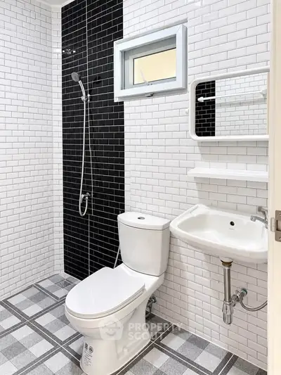 Modern bathroom with sleek black and white tiles, featuring a shower, toilet, and sink.