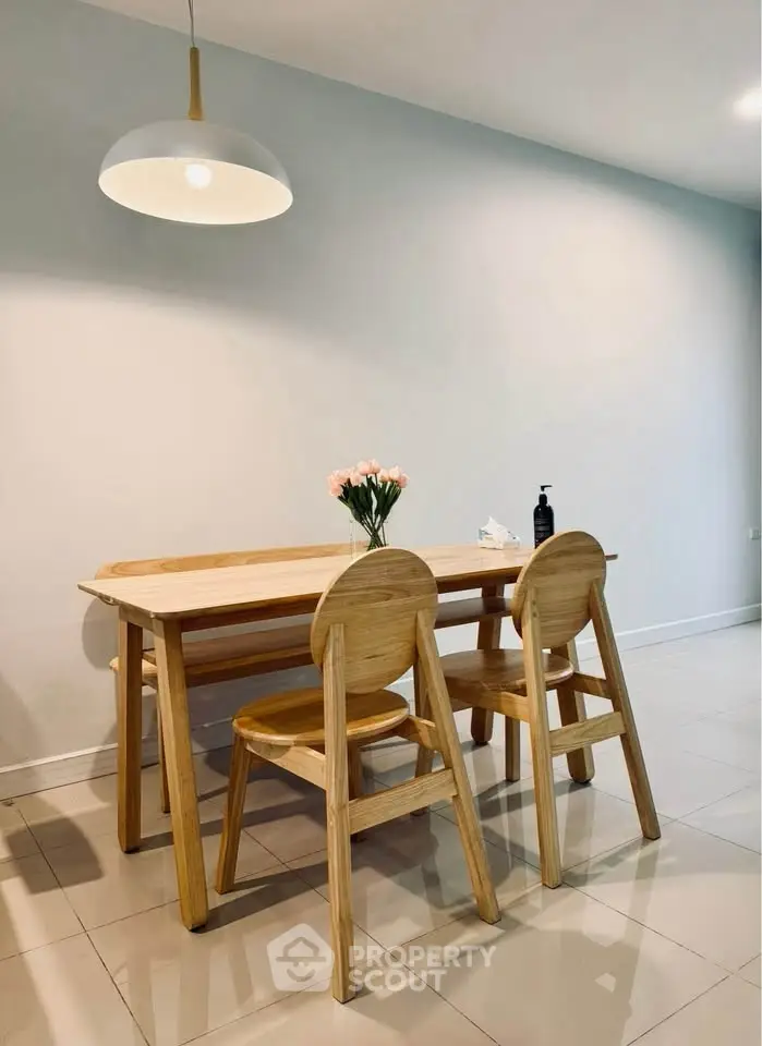 Modern dining area with wooden table and chairs, elegant lighting, and minimalist decor.