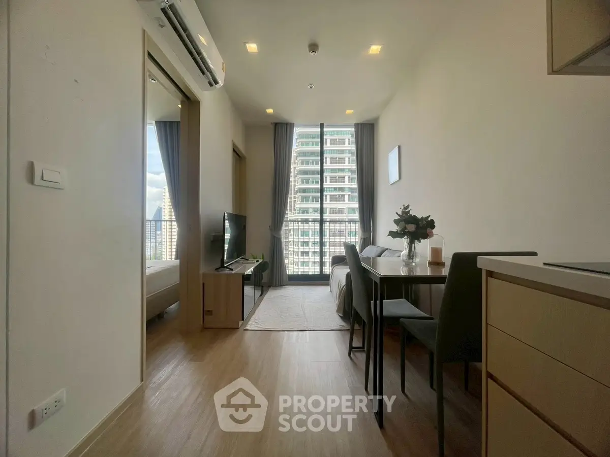 Modern apartment interior with open layout, featuring a cozy living area and dining space with city view.