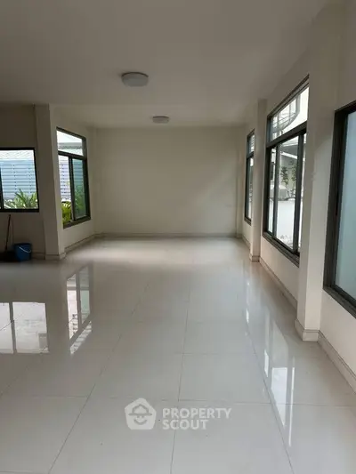 Spacious empty room with large windows and glossy tile flooring, ideal for customization.