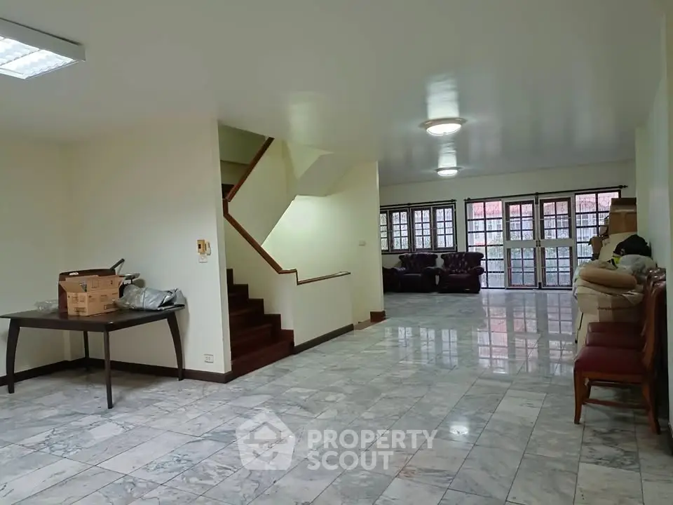 Spacious open-plan living area with marble flooring and ample natural light.