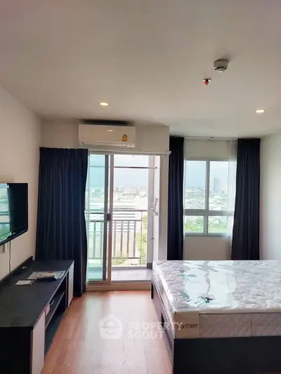 Modern bedroom with balcony and city view, featuring sleek furniture and natural light.