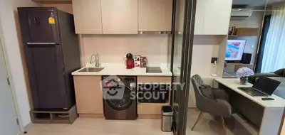 Modern kitchen with sleek appliances and adjacent study area in stylish apartment.