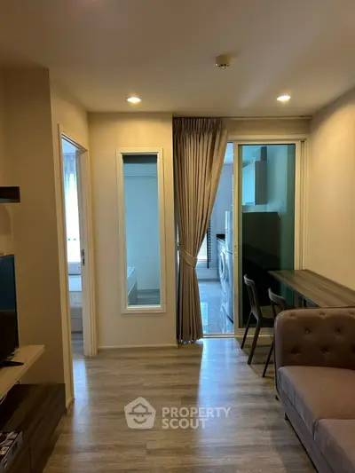 Modern living room with open layout and washing machine in view, featuring sleek furniture and natural lighting.