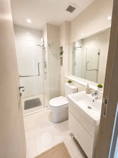 Modern bathroom with sleek design, featuring a glass shower and elegant fixtures.