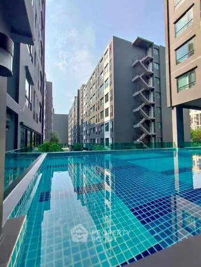 Modern apartment complex with a stunning outdoor pool reflecting the clear blue sky.
