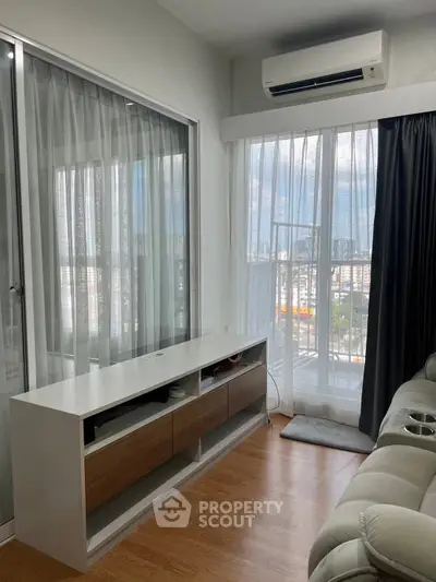 Modern living room with large windows and air conditioning, featuring a sleek TV stand and comfortable seating.