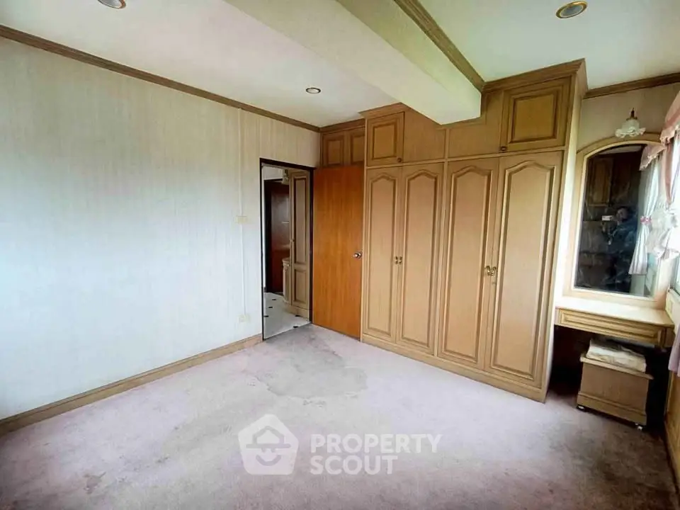Spacious bedroom with built-in wooden wardrobe and vanity, ideal for customization.