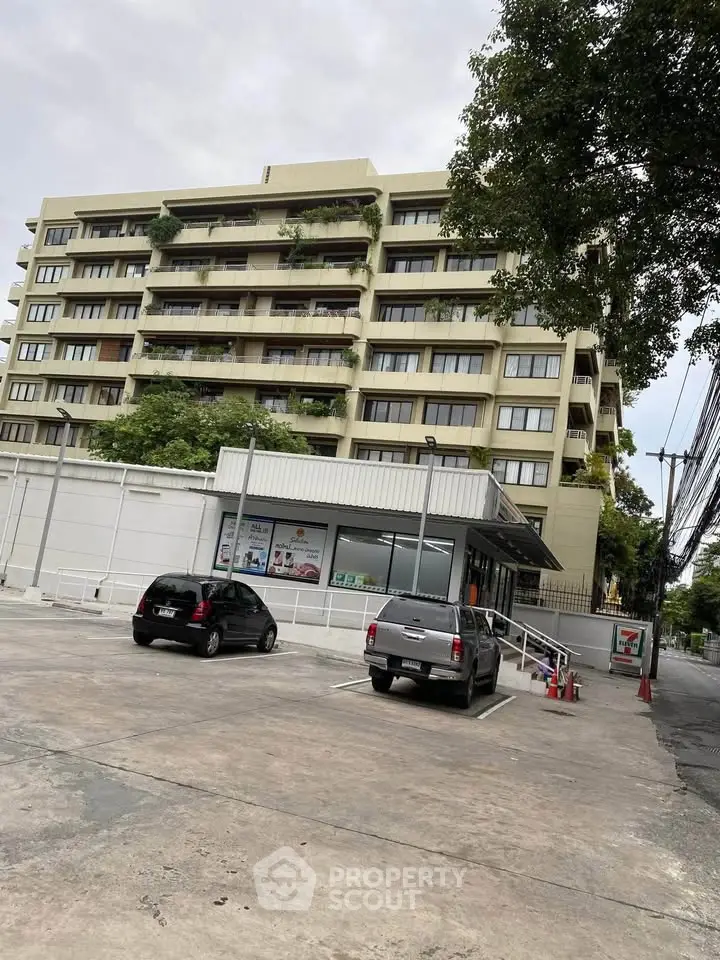 Modern apartment building with parking area and lush greenery, ideal for urban living.