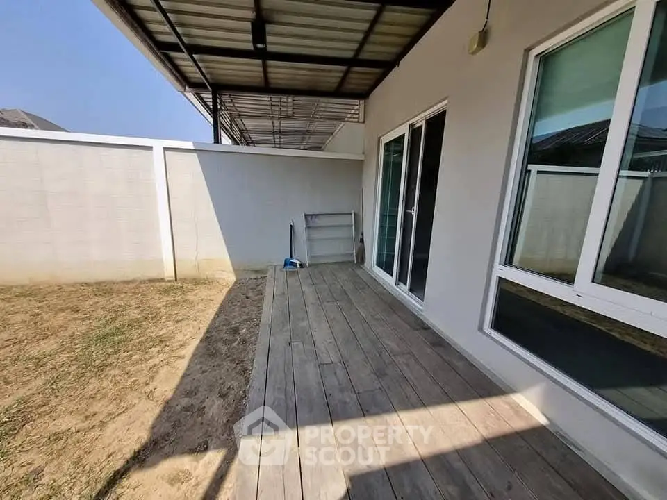 Spacious backyard patio with wooden deck and sliding glass doors in modern home.