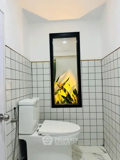 Modern bathroom with stylish tiled walls and a window view of lush greenery.