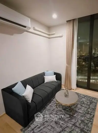 Modern living room with city view, featuring a sleek black sofa and stylish decor.