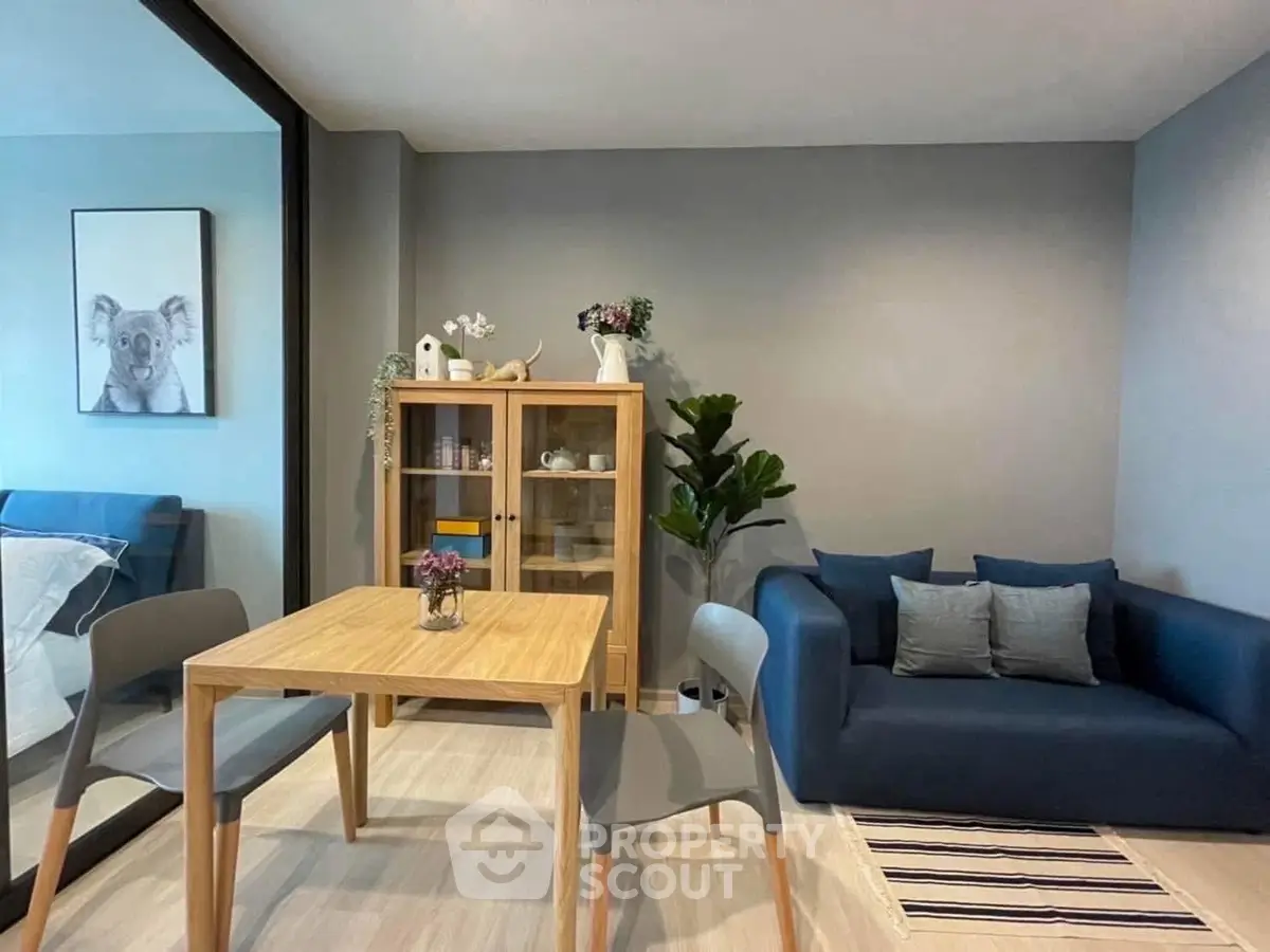 Modern living room with stylish furniture and cozy decor, featuring a blue sofa and wooden dining table.