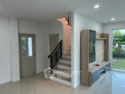 Modern interior with sleek staircase and built-in wooden entertainment unit.