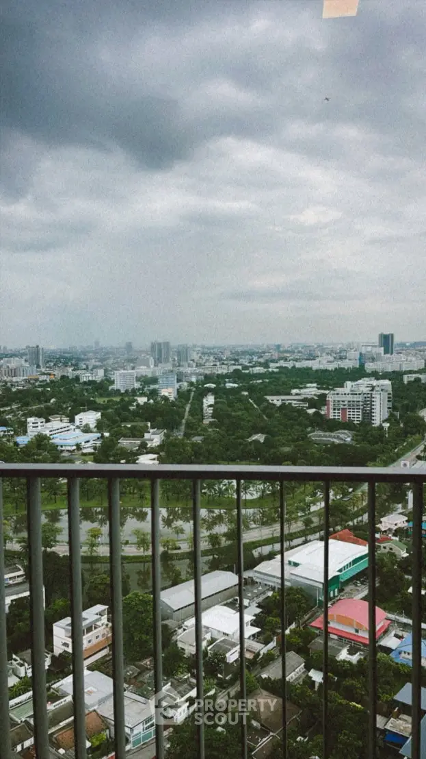 Stunning cityscape view from a high-rise balcony with lush greenery and urban skyline.