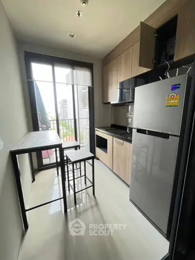 Modern compact kitchen with sleek appliances and city view from large window.