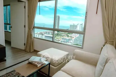 Modern living room with stunning city and ocean view from large window, featuring cozy seating and stylish decor.