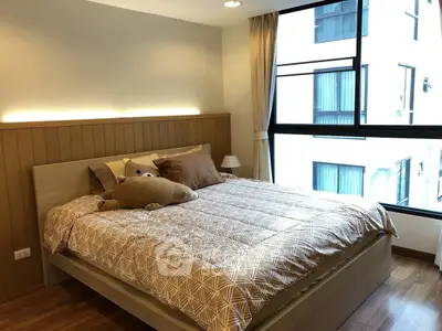 Cozy bedroom with large window and stylish decor in modern apartment