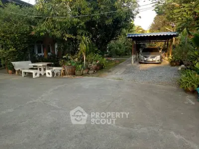 Charming garden view with carport and outdoor seating area in serene residential setting.