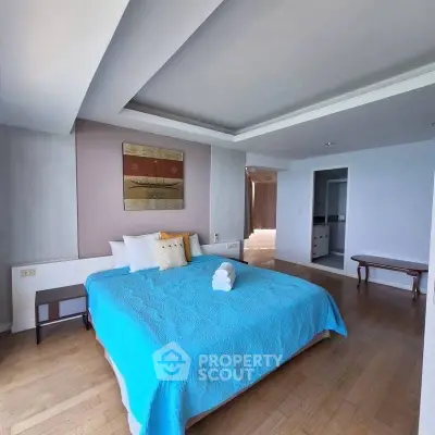 Spacious bedroom with modern decor and blue bedding in a luxury apartment.
