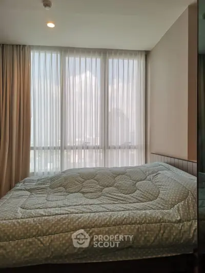 Bright bedroom with large windows and cozy bedding, offering a serene and inviting atmosphere.