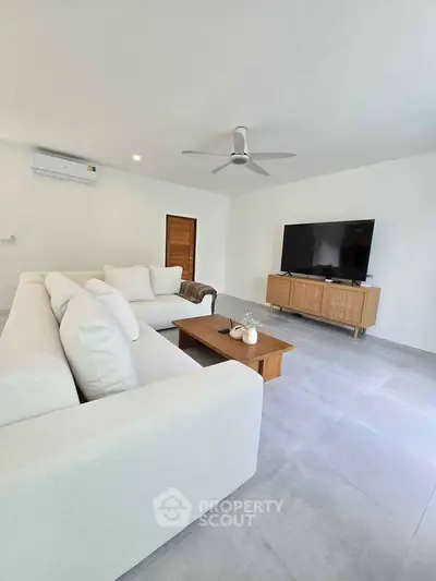 Spacious modern living room with sleek furniture and large TV