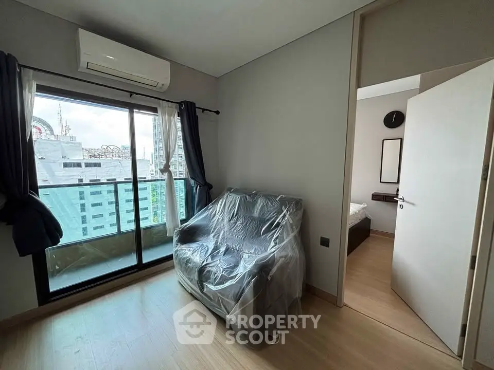 Modern apartment with balcony and city view, featuring a cozy living area and bedroom access.
