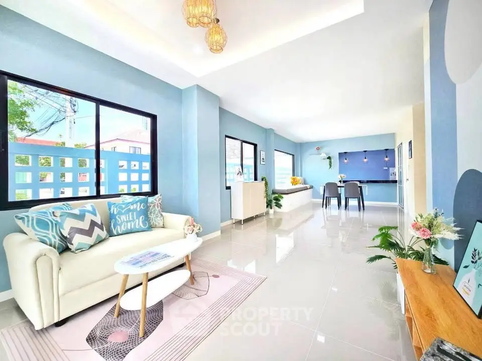 Spacious modern living room with elegant decor and open dining area, featuring large windows and stylish lighting.