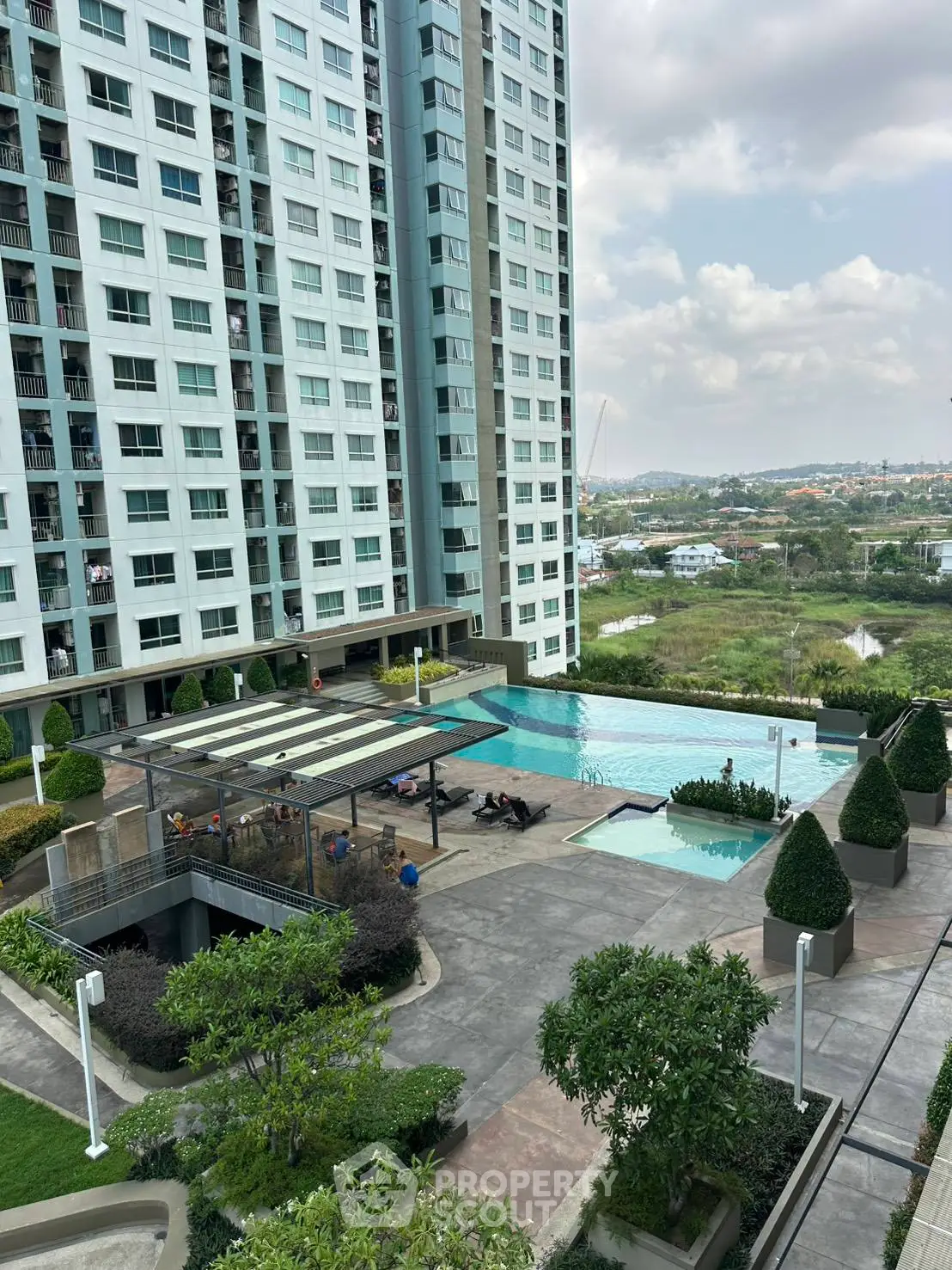 Modern high-rise building with pool and landscaped garden offering stunning city views.