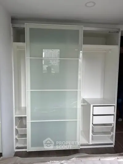 Spacious modern wardrobe with sliding glass doors and organized storage solutions.