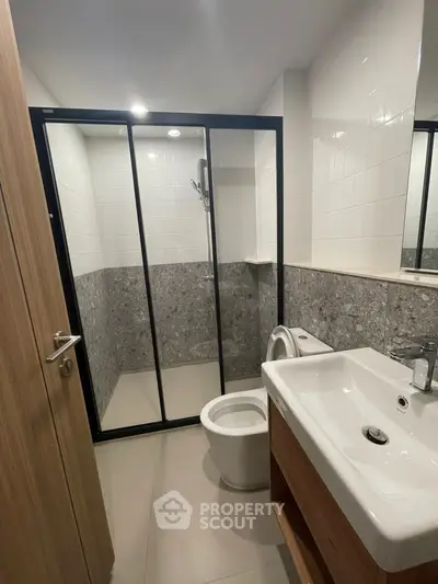 Modern bathroom with sleek shower and stylish sink in contemporary apartment.
