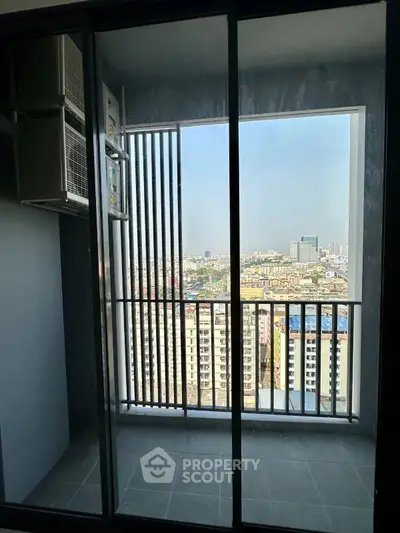 Modern balcony with cityscape view through glass doors in high-rise apartment.