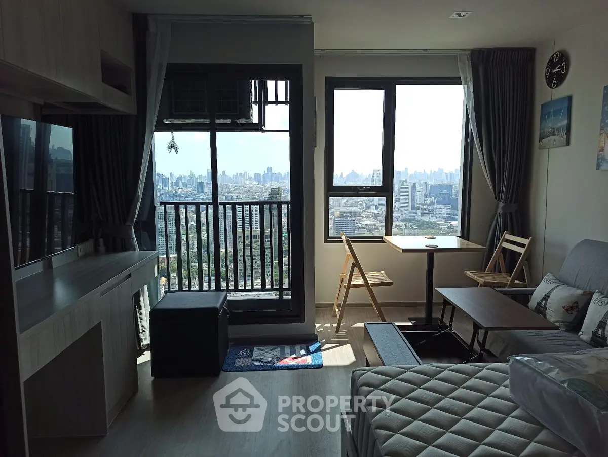 Modern living room with city view, featuring stylish furniture and large windows for natural light.