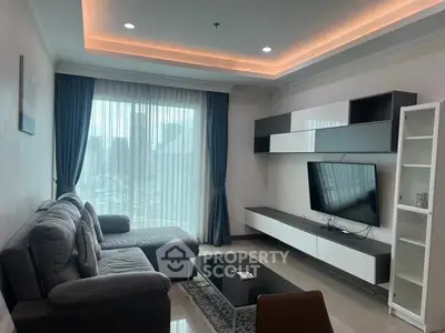 Modern living room with sleek furniture and city view, featuring a cozy sectional sofa and mounted TV.