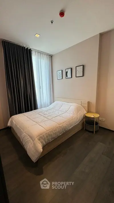 Modern bedroom with cozy bed, stylish decor, and natural light through large window.