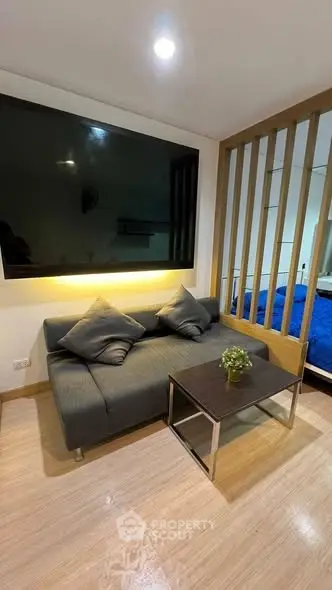 Modern living room with sleek sofa, large TV, and stylish partition in cozy apartment.