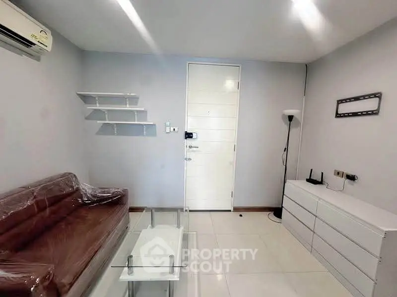 Modern living room with sleek furniture and minimalist design, featuring a brown sofa and glass coffee table.