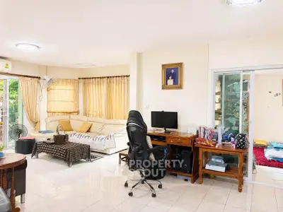 Spacious living room with cozy seating and home office setup, perfect for modern living.
