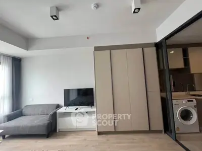 Modern living room with sleek furniture and integrated kitchen appliances in a stylish apartment.