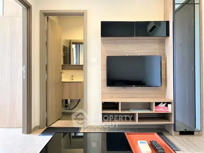 Modern living room with wall-mounted TV and view into a stylish bathroom.