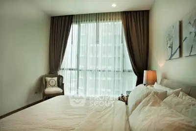 Elegant bedroom with large window and cozy decor in modern apartment.