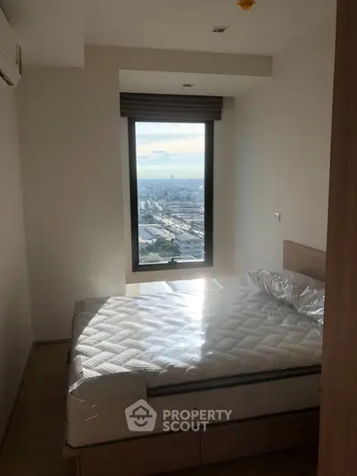 Cozy bedroom with stunning city view through large window, featuring a comfortable bed and modern decor.