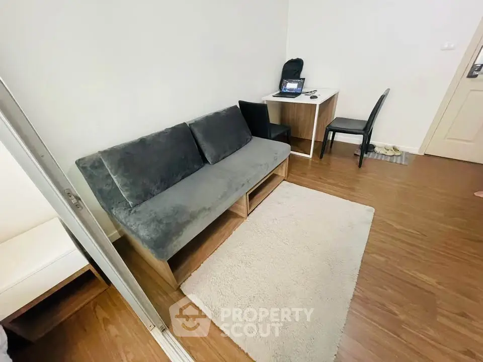 Cozy living room with modern sofa and workspace, perfect for urban living.