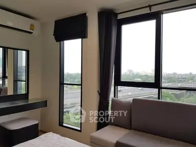 Modern bedroom with large windows offering a stunning city view, featuring sleek furniture and stylish decor.